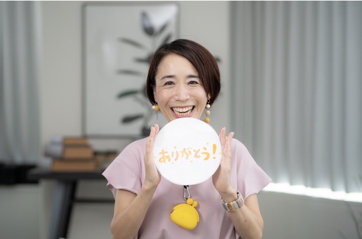 ありがとうの札を持って笑顔を見せる土居由紀子
