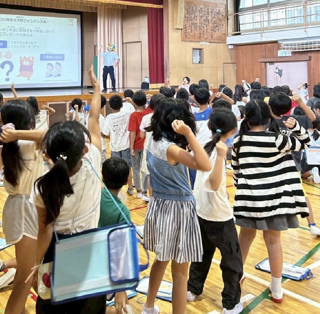 小学校の体育館で多数の子どもたちが参加する金融教育講座